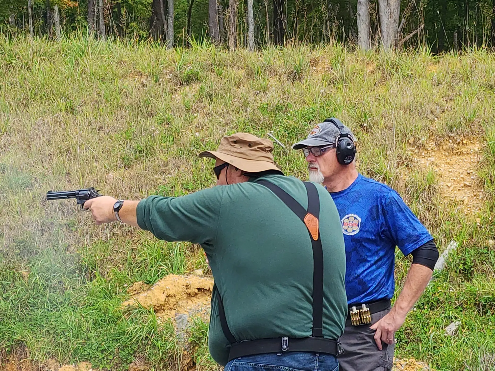 A competitor fires a revolver at the ICORE East Coast Regional as a range officer watches. Tri-Angle Sportsmen's Club, Bluefield, Virginia